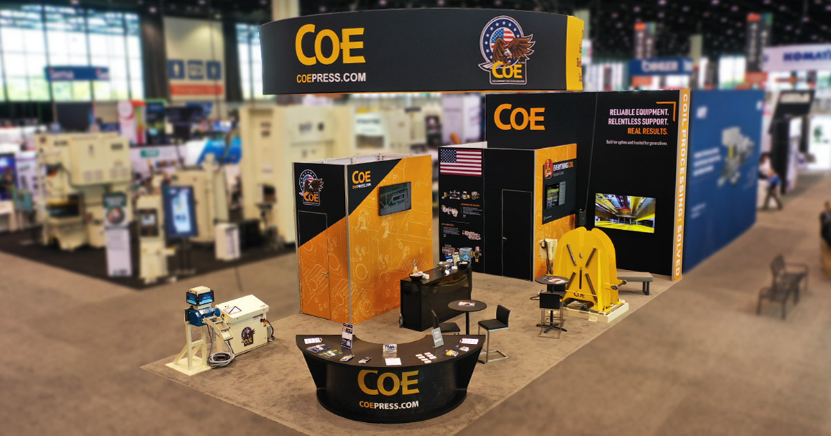 COE at FABTECH 2025 in Chicago, Illinois - COE Press Equipment trade show booth with black-and-yellow graphics, an overhead hanging sign reading “The Science Behind the Solution,” COE-branded counters and wall displays, and machinery exhibits on the show floor.