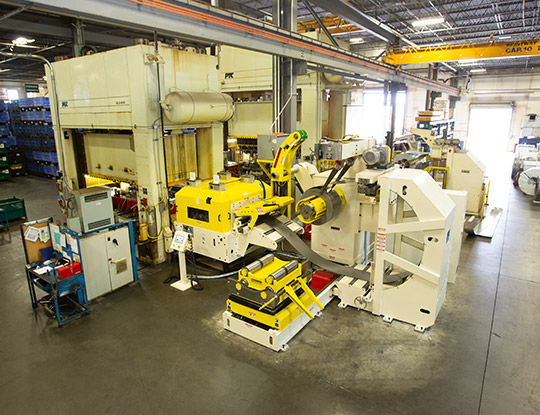 COE compact coil feed line installed on a factory floor at Nahanni Steel Products, with a yellow-and-white decoiler, straightener/feeder, and control equipment set up for processing AHSS.