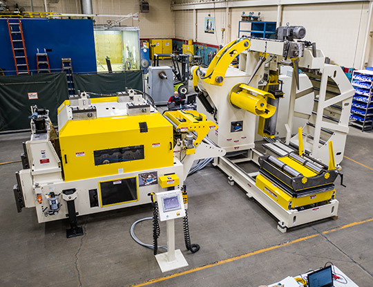 High strength steel stamping compact line being assembled in COE Press Equipment’s assembly shop in Sterling Heights, Michigan, featuring a yellow servo feed and coil handling system.
