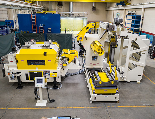 High strength steel stamping compact line being assembled in COE Press Equipment’s assembly shop in Sterling Heights, Michigan, featuring a yellow servo feed and coil handling system.