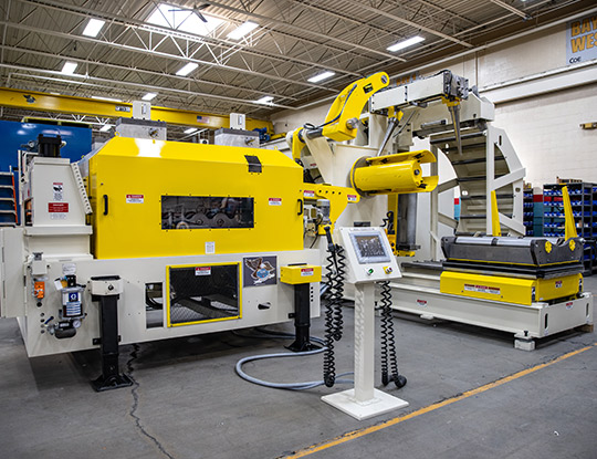High strength steel stamping compact line being assembled in COE Press Equipment’s assembly shop in Sterling Heights, Michigan, featuring a yellow servo feed and coil handling system.