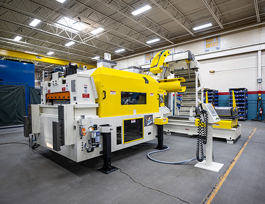 High strength steel stamping compact line being assembled in COE Press Equipment’s assembly shop in Sterling Heights, Michigan, featuring a yellow servo feed and coil handling system.